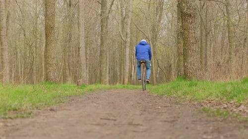 Man Riding Vintage Road Bike From Camera Through Forest