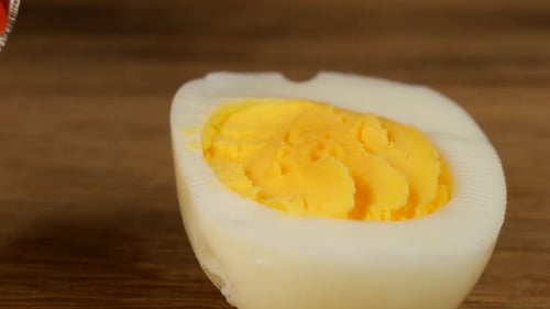 Hälften eines hartgekochten Hühnereies mit rotem Kaviar auf einem hölzernen Hintergrund.