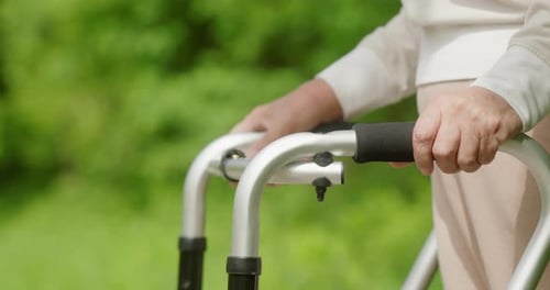 A Senior Uses a Walker Outdoors in a Vibrant Sunny Setting Showing Commitment to an Active Life