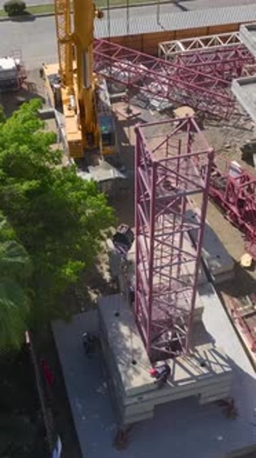 Vertical Video Construction Workers Assembling A Tall Crane OnSite Focusing On Detail And Safety