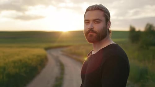 Bel homme posant devant la caméra pendant le coucher du soleil sur le terrain