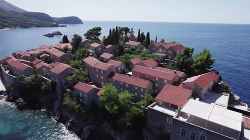 A drone flies over the island of Sveti Stefan on a sunny day in Montenegro