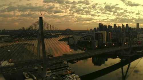 Drone aerial view of traffic flowing over a suspended bridge across a river. Waterfront homes, boats