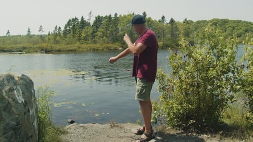 Man Sprays Mosquito Repellent Near Lake on a Clear Day