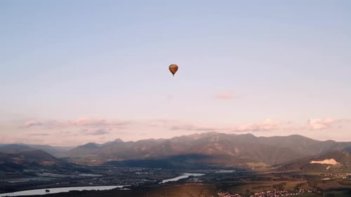 Panoramic aerial view of hot air balloon floating in golden hour sky
