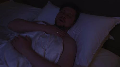 Restless Man Experiencing Breathing Problems and Sleep Apnea Symptoms Moving and Gasping for Air in