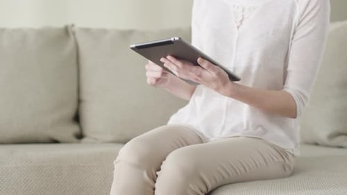 Woman Using Tablet on Couch in Bright Home