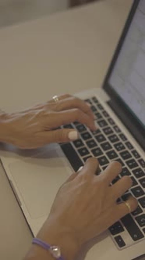 Female hands typing on laptop at desk, close up view