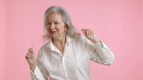 Senior Woman Dancing and Smiling on Pink Background