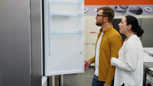 Young Couple in Appliances Store Choose to Buy Fridge for Home