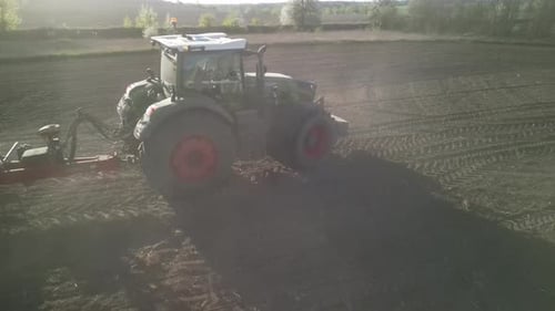 Green tractor works on the field sowing sunflower. Tractor planting corn in Ukraine