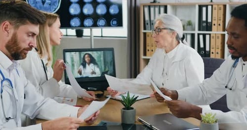 Multiethnic doctors working together with different medical reports during joint meeting in clinic
