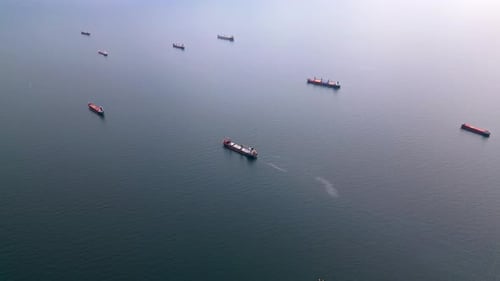 Luftaufnahme mehrerer Frachtschiffe, die über das ruhige offene Meer verstreut sind Die Höhepunkte der maritimen Szene