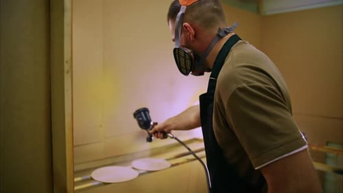 Craftsman sprüht Farbe auf runde Holzoberflächen