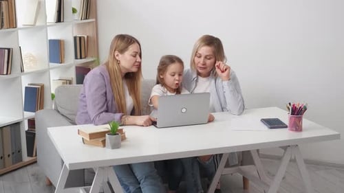 Child, Adult, and Senior Look at Laptop Together