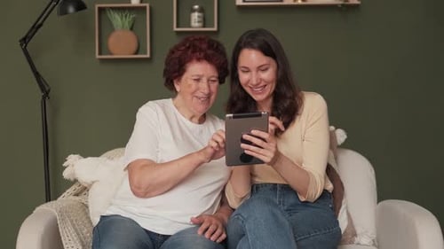 Senior Woman and Young Adult Looking at Tablet
