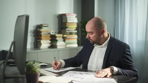 A Businessman Makes Notes in a Notebook at the Workplace in the Office