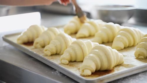 Female Baker Smears Raw Croissants with a Brush Cooking Process
