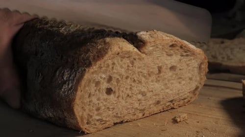 Slicing Fresh Bread Loaf with Knife on Board