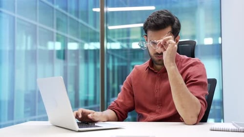 Young Man Working at Desk Gets Headache