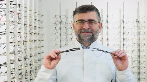 Oftalmólogo senior de los años 50 y 60 sostiene las gafas en las manos
