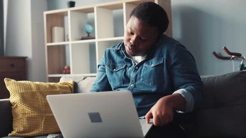 Man Works on Laptop and Talks on Phone