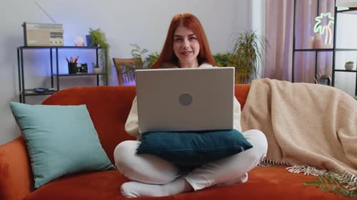 Woman Opens Laptop on Couch in Cozy Home