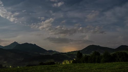 Tempestade de verão está chegando com nuvens escuras e relâmpagos no campo noturno e montanhas Time Lapse