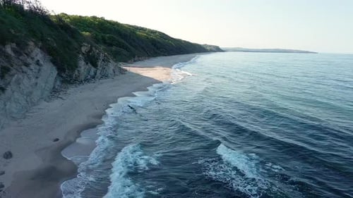 Felsvorsprung mit Vegetation über Strand im Schatten in der Nähe des Schwarzen Meeres unter blauem Himmel