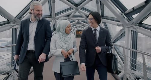 Group of Joyful Businesspeople Walking in Futuristic Glass Hall Celebrating Professional Success