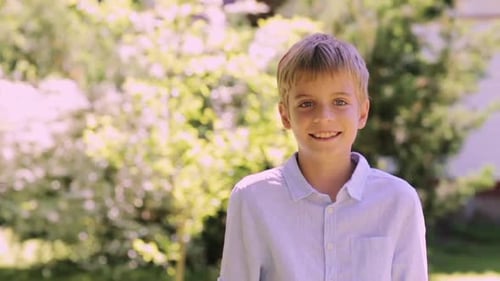 Happy smiling preteen boy enjoying summer sunshine in a beautiful garden