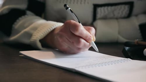 Woman Writing Notes in a Spiral Notebook