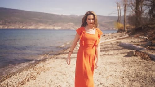 Pretty girl wearing red dress on a windy beach in slow motion