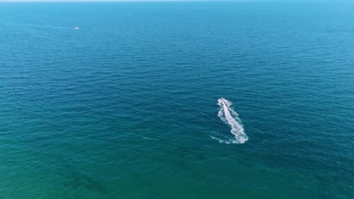 Following a jet ski scooter riding by the beautiful blue waterscape.