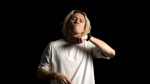 Un homme blond aux cheveux longs menace de violence, fond noir
