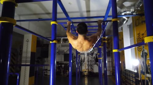 Young Muscular Athlete Showing Some Gymnastics Stunts on Horizontal Bar at Sport Club Strong Sporty