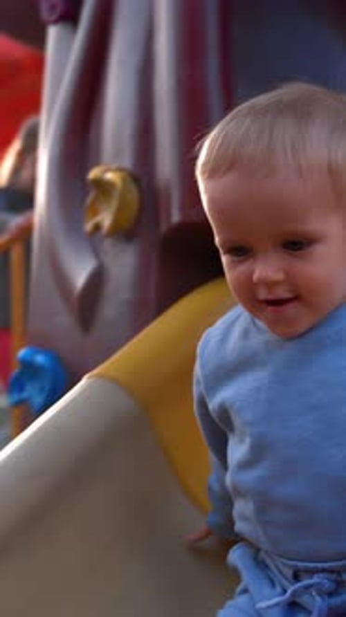 Vertical of Kid Slides Down Colorful Slide Installed at Playground