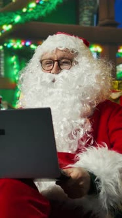 Vertical Video Santa Claus Doing Internet Videocall with Kids on Laptop From Cozy Christmas Set