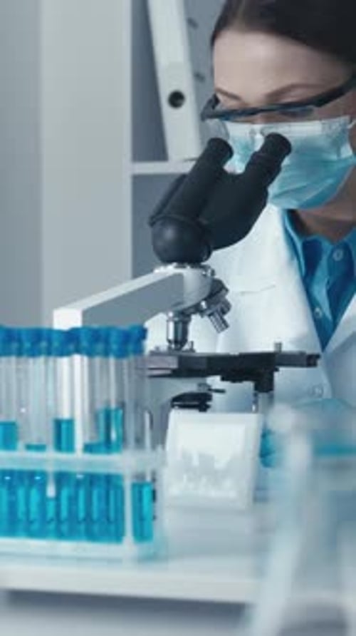 Woman Using Microscope in a Laboratory Setting