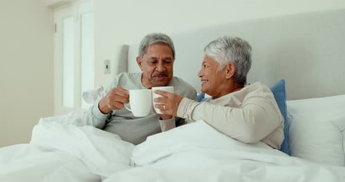 Affectionate Senior Couple Cuddling in Bed With Coffee