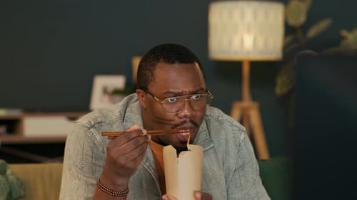 Man Eating Chinese Noodles, Watching Horror Movie and Expressing Fear