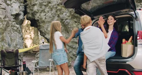 Wonderful young family man woman and children on vacation in forest next to parked car.