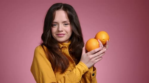 Smiling Woman Holding Two Oranges