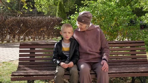 Portrait of a Little Boy with His Grandmother in the Park on a Bench