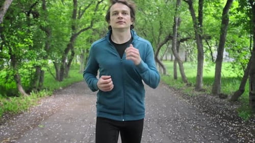 Sportive young man running. Young man runs in the park during the day