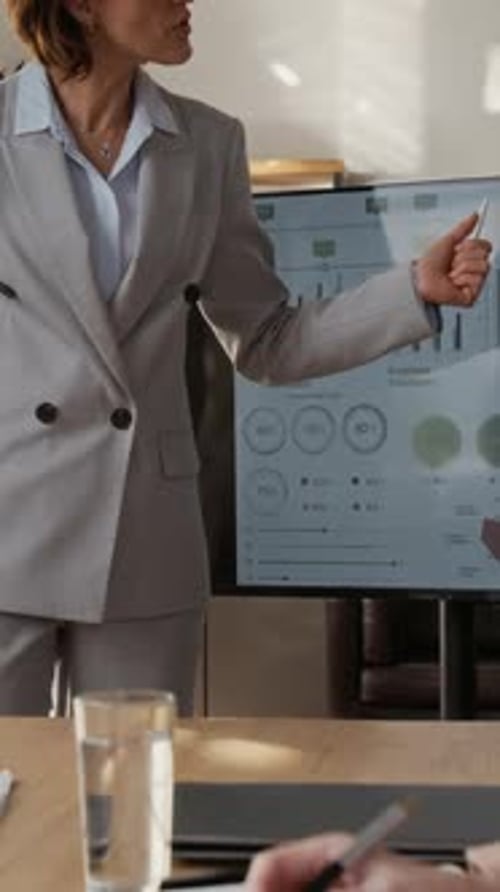 Woman Showcasing Corporate Graphs and Data to her Colleagues at Desk in Office