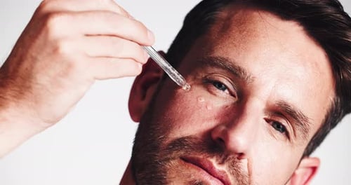 Man, face and oil with serum dropper for vitamin c, collagen or dermatology on a white studio