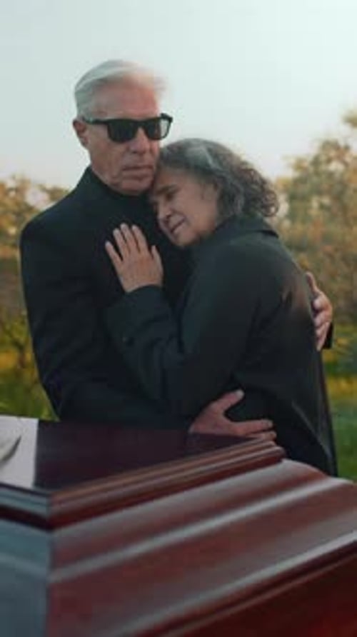 Grieving Couple Embracing Near Coffin