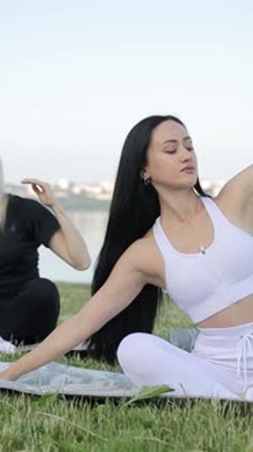 Beautiful Women Doing Yoga or Stretching on the Green Grass Near the Lake Vertical Video