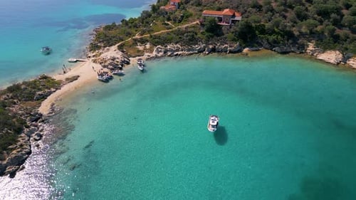 Aerial View of a Stunning Turquoise Bay Dotted with Boats Surrounded By Rugged Coastline and Olive